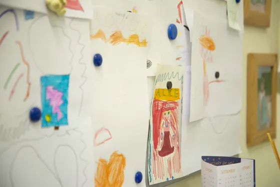 Disegni di bambini appesi con le calamite su una lavagna bianca