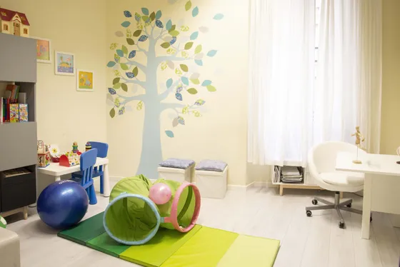 Stanza per bambini con un albero dipinto sulla parete, tappeti morbidi e palloni