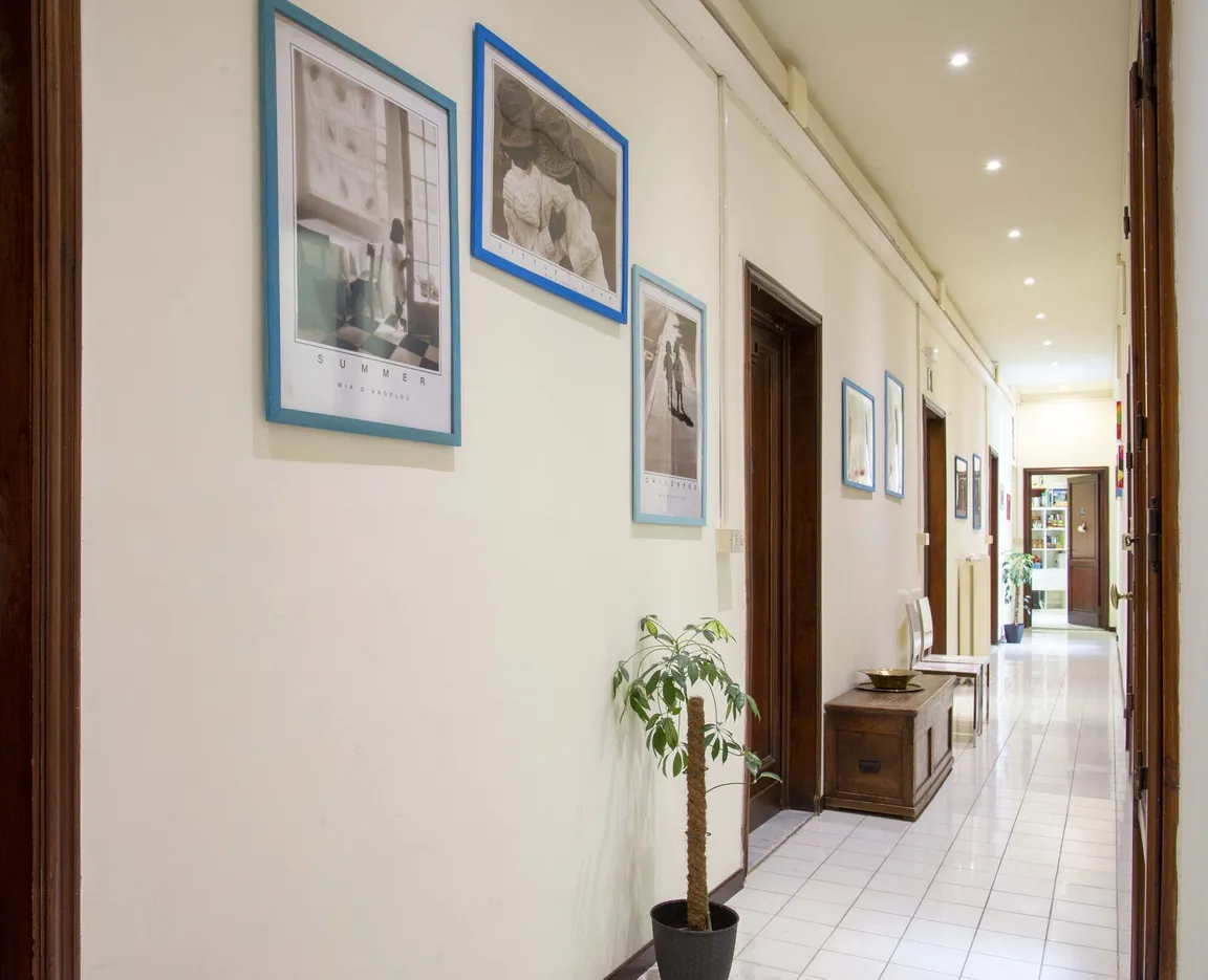 Il corridoio luminoso dello studio, con quadri alle pareti e le porte delle stanze