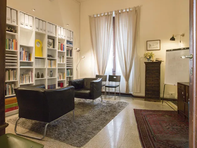 Stanza per i colloqui con poltrone in pelle, libreria bianca e tappeto