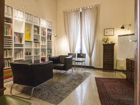 Stanza per i colloqui con poltrone in pelle, libreria bianca e tappeto