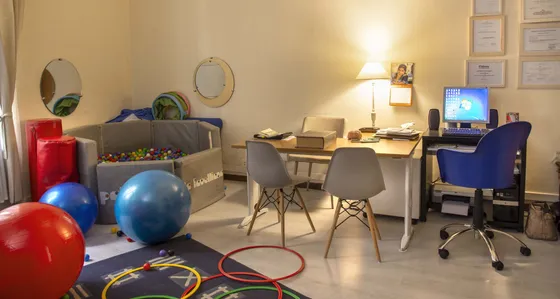 Sala di psicomotricità con palle colorate, cerchi a terra e un tavolo
